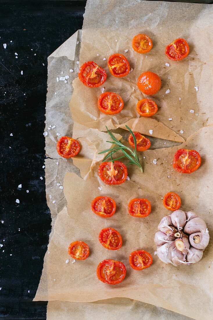 Baked cherry tomatoes with salt and garlic on backing paper
