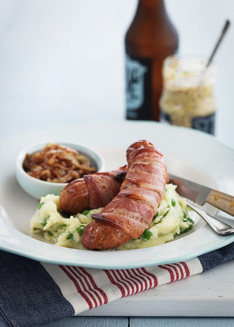 Sausages wrapped in bacon on a bed of mashed potatoes