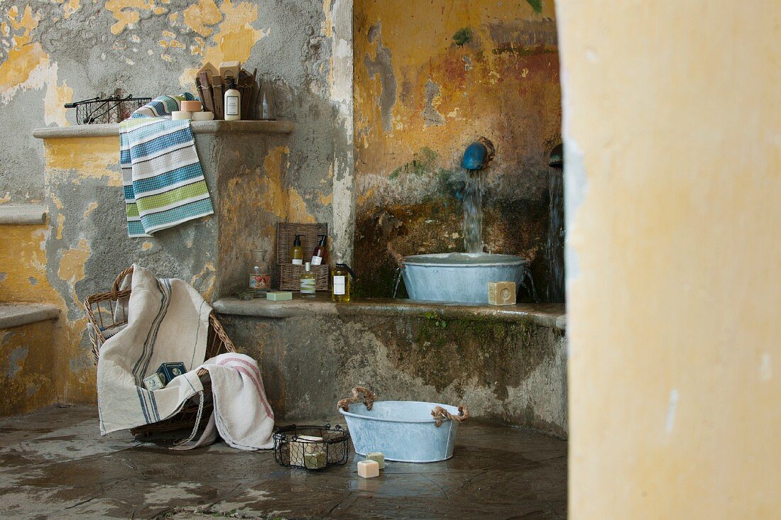 Waschbereich in Shabby Ambiente, Vintage Zinkwanne auf Steinbank unter Wasserspeier in französischem mediterranem Flair