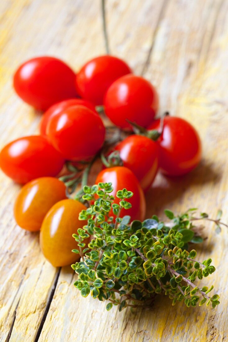 Cherry tomatoes and lemon thyme on a wooden surface