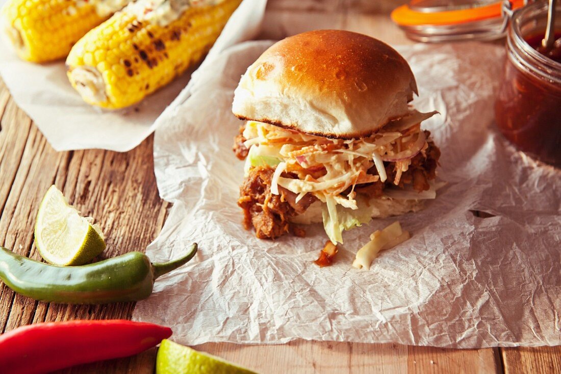 A pulled pork slider with apple coleslaw and grilled corn cobs (USA)