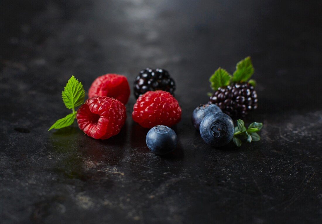Fresh raspberries, blueberries and blackberries with leaves