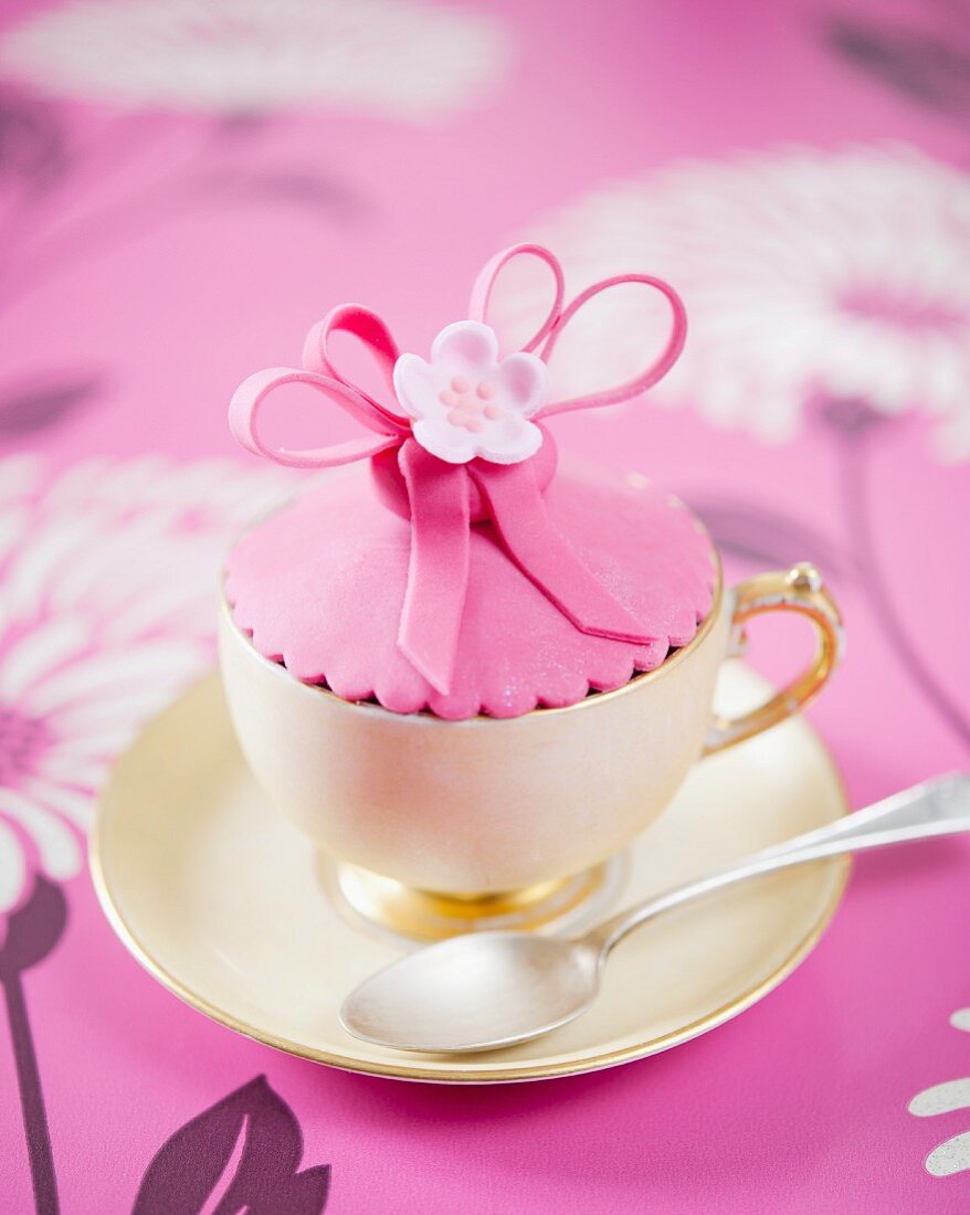 A pink flower cupcake in a cup