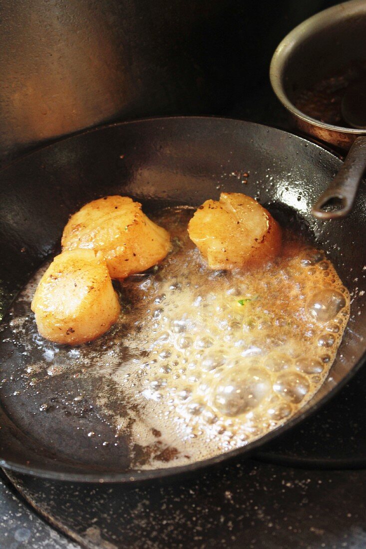 Scallops being fried in a pan
