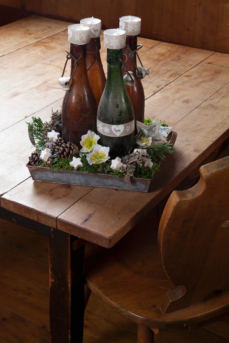Rustic Advent wreath made from four old swing-top bottles and tealights on metal tray
