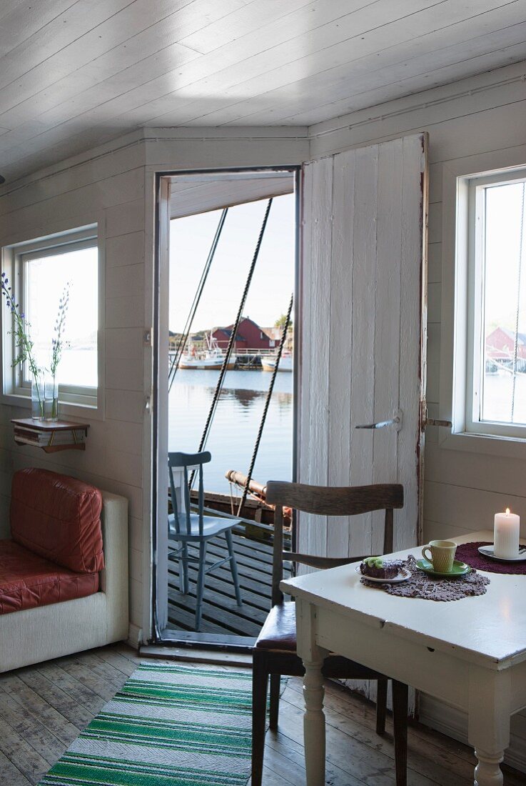 Table set with coffee service in front of open door with view of jetty and sea