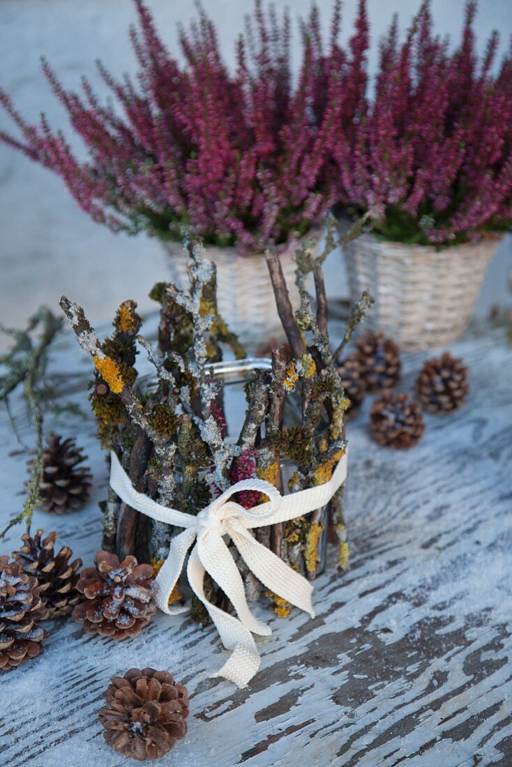 Tealight holder decorated with twigs and lichen in front of pink heathers
