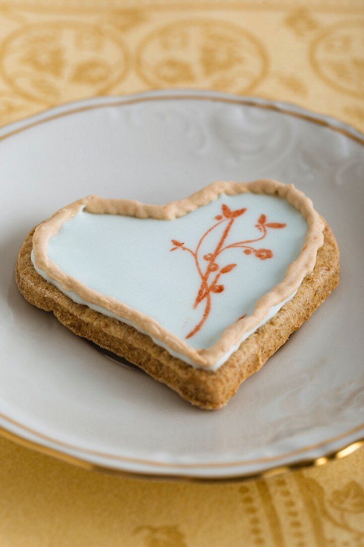 A heart-shaped biscuit with an egg white glaze and a stamped motif