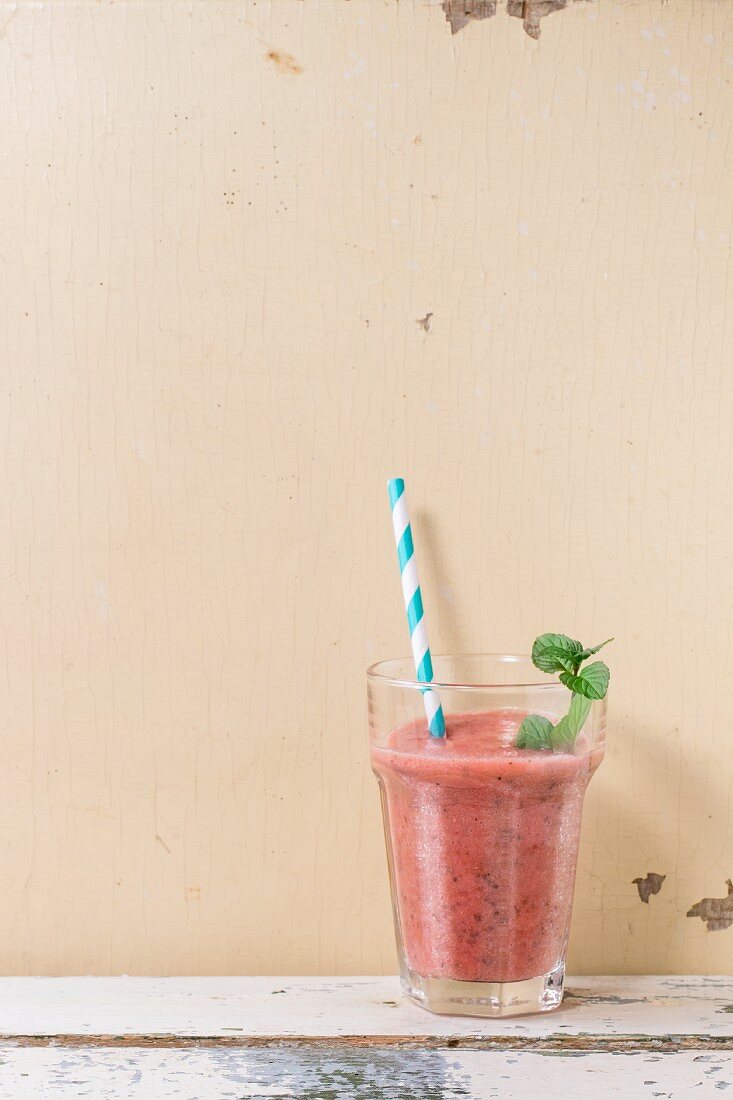 A glass of strawberry smoothie with chia seeds and fresh mint