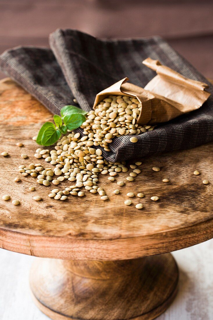 Dried lentils with a paper bag on a wooden cake stand