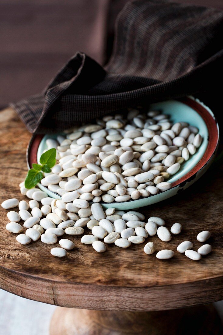 Dried white beans on a plate on a wooden cake stand