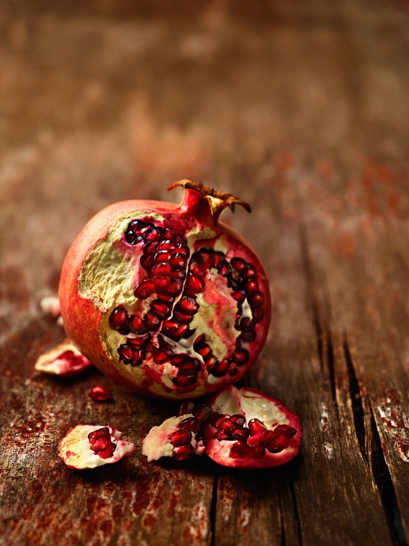 A pomegranate, sliced, on a wooden surface