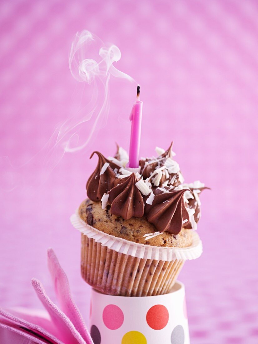 Geburtstags-Cupcake mit rauchender Geburtstagskerze