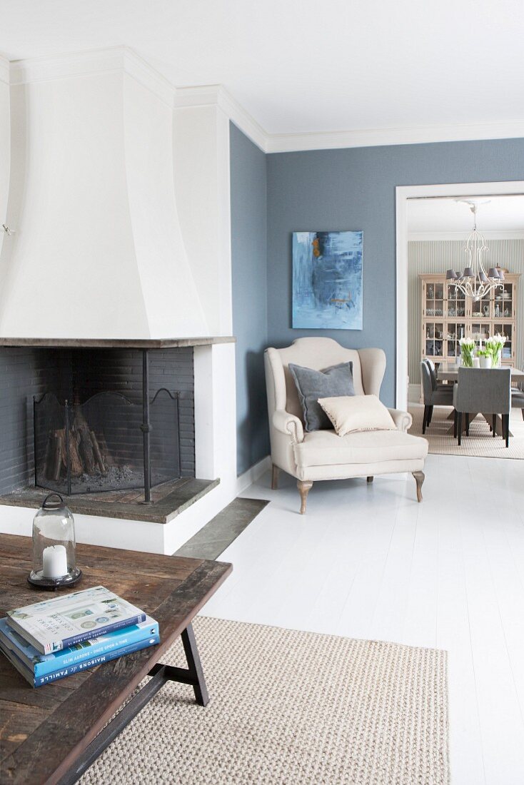 Open-plan living area with fireplace and elegant armchair in corner against slate grey walls