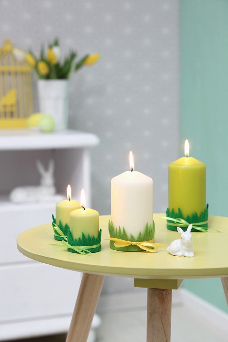 Easter arrangement in shades of green; candles trimmed with felt grass and rabbit ornament on small, round table