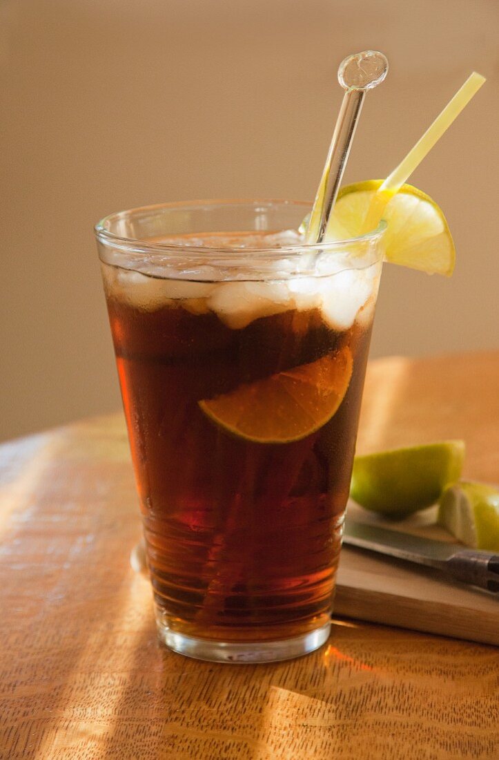 Cola with rum, limes and ice cubes in a ray of sunshine