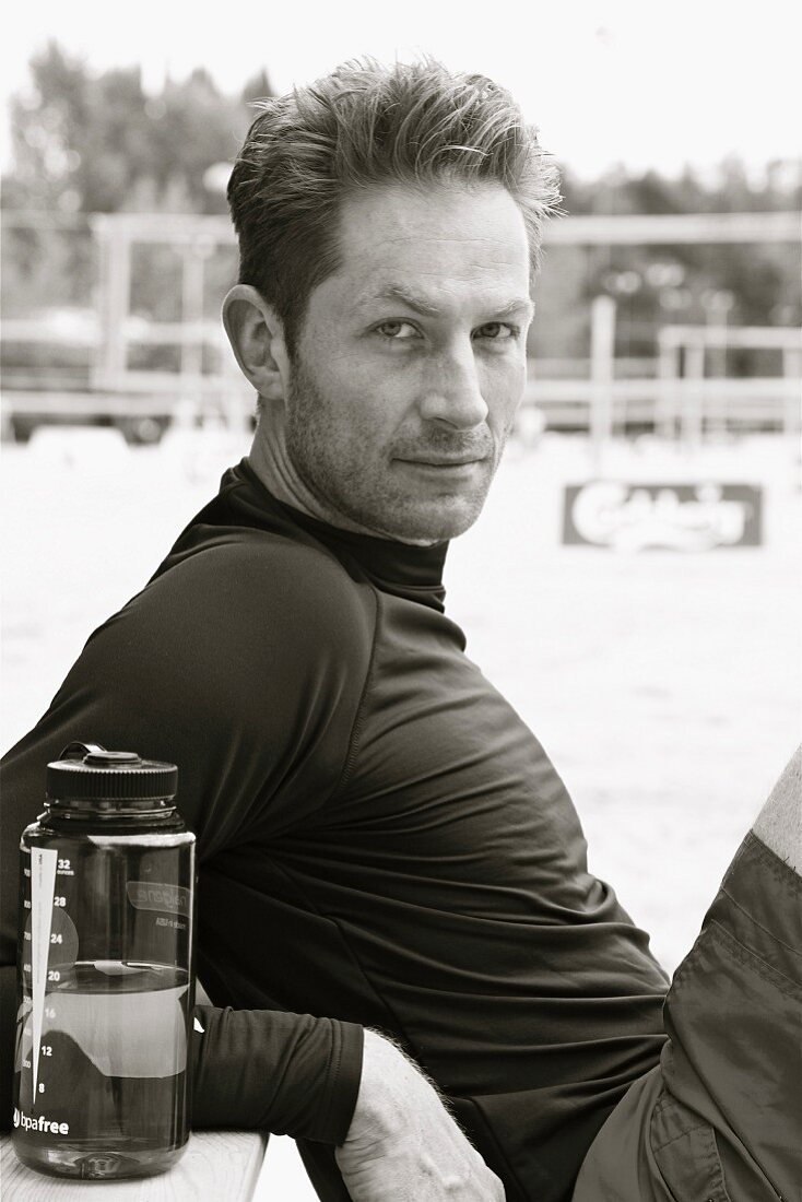 A man wearing dark sports clothes with a water bottle (black-and-white shot)
