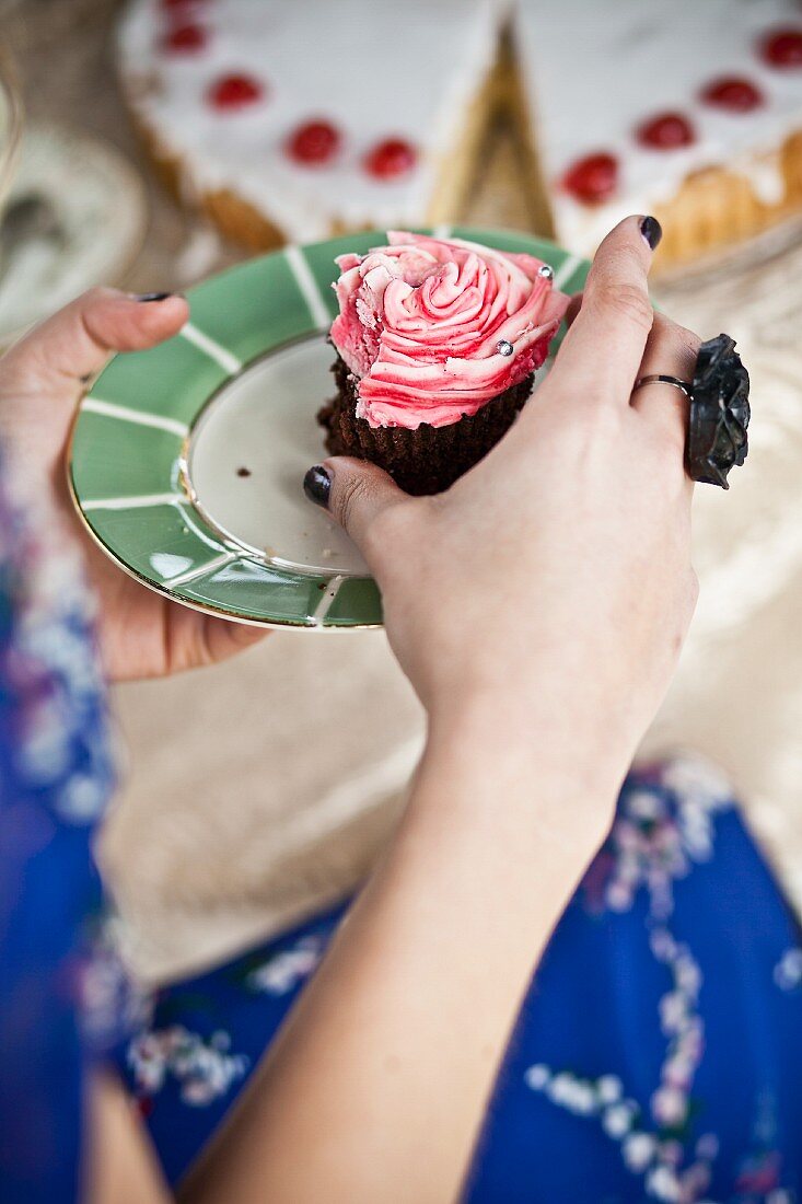 A woman eating a pink cupcake