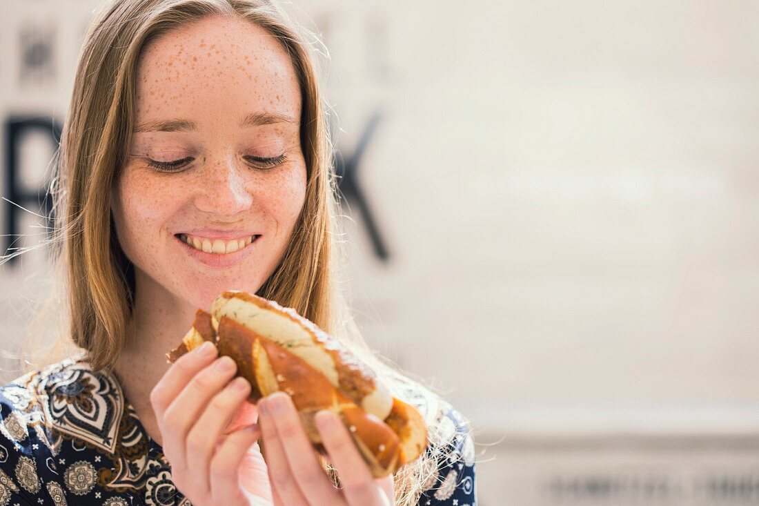 Junge Frau mit Weisswurst-Hotdog