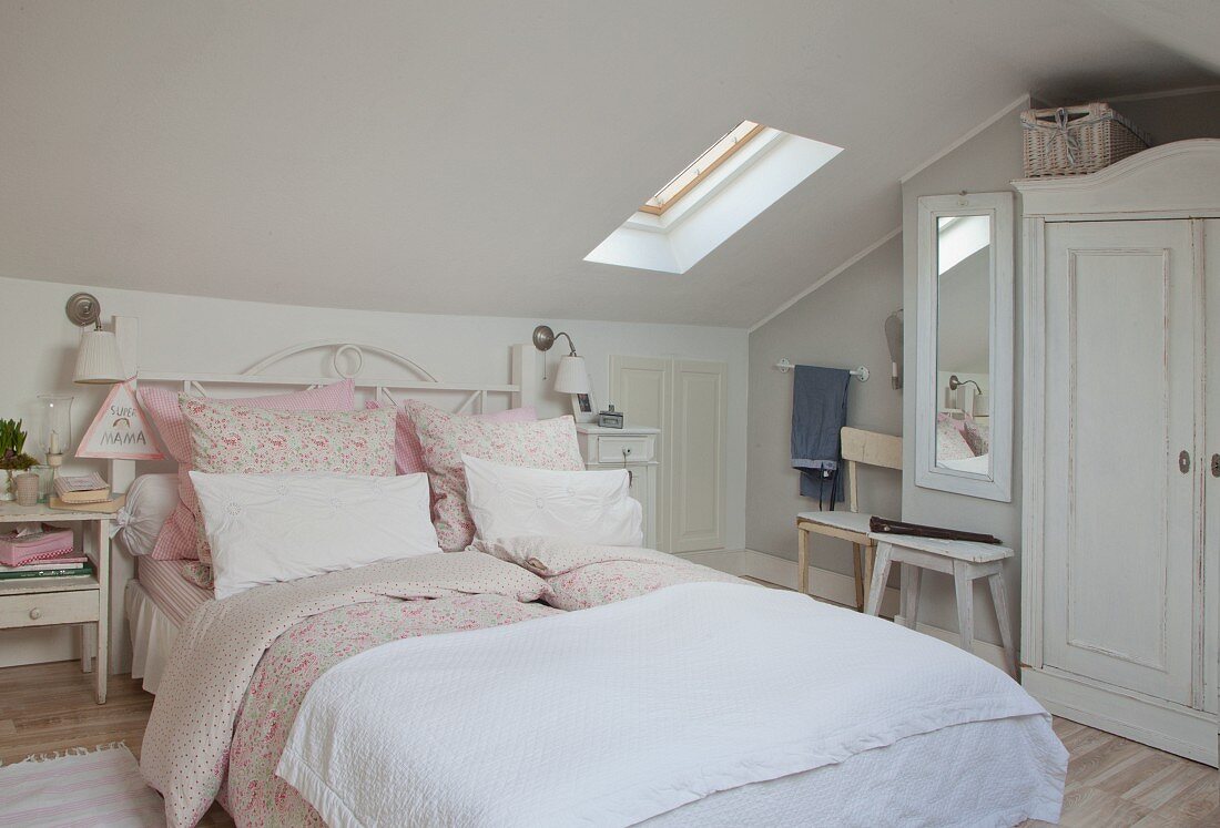 Romantic double bed with pink bed linen in shabby-chic attic room