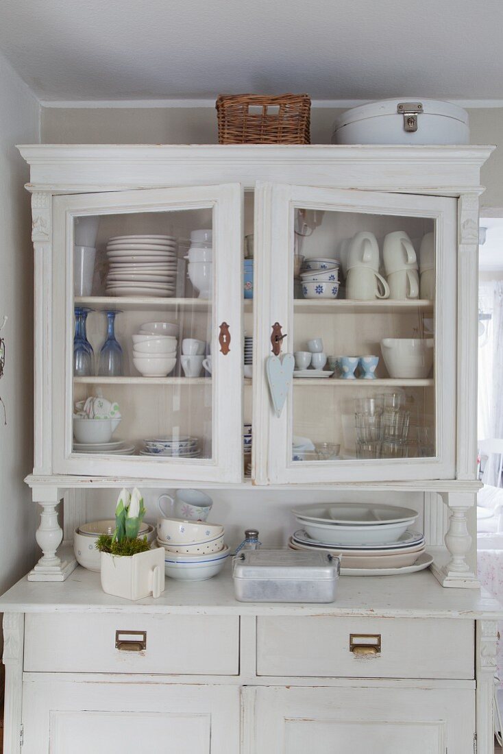 Crockery and spring flowers on and in shabby-chic dresser