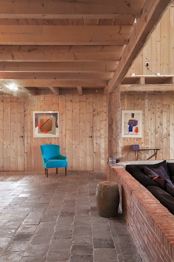Turquoise armchair in renovated, wood-clad interior