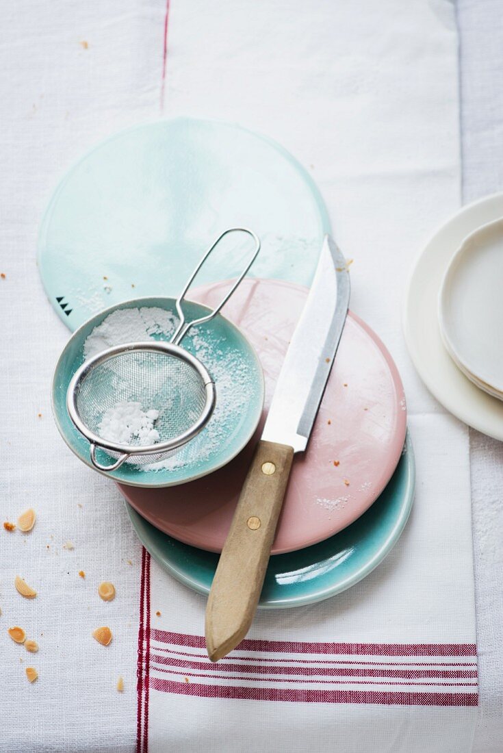 Cake plates and a sieve with icing sugar in a bowl