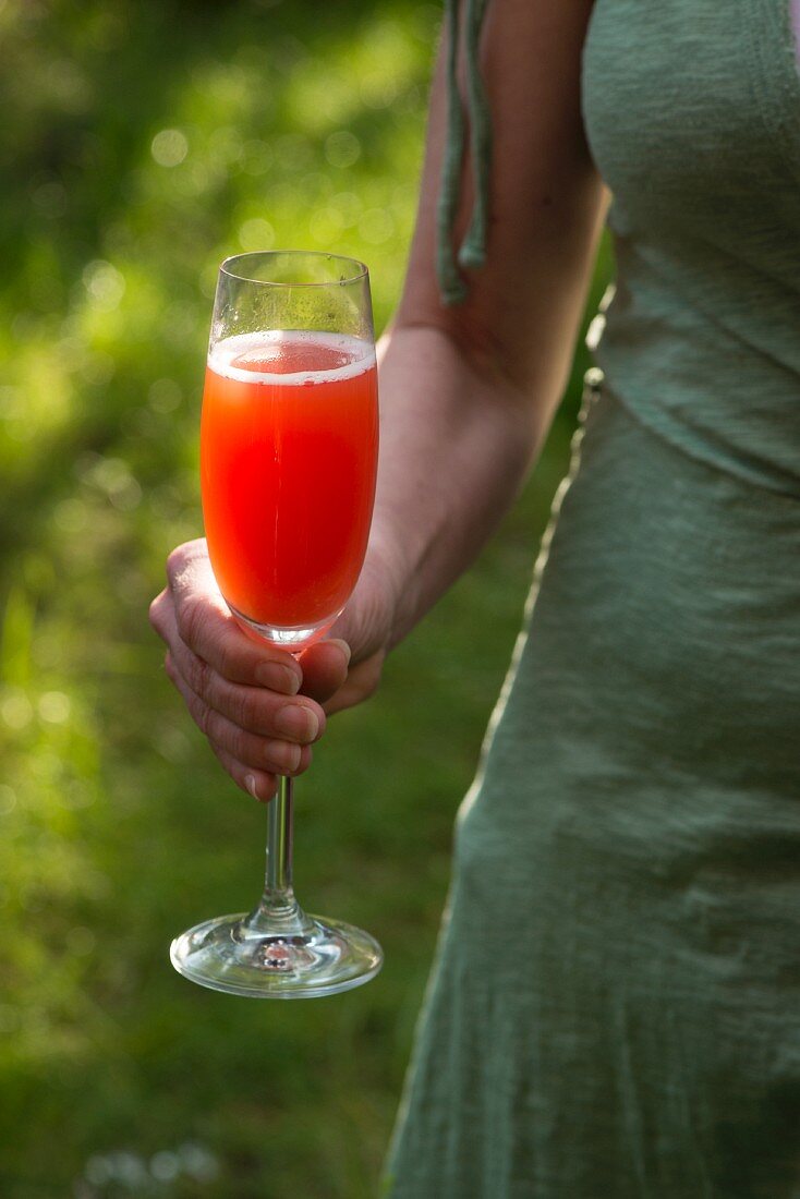 A woman holding a glass of Aperol Spritz