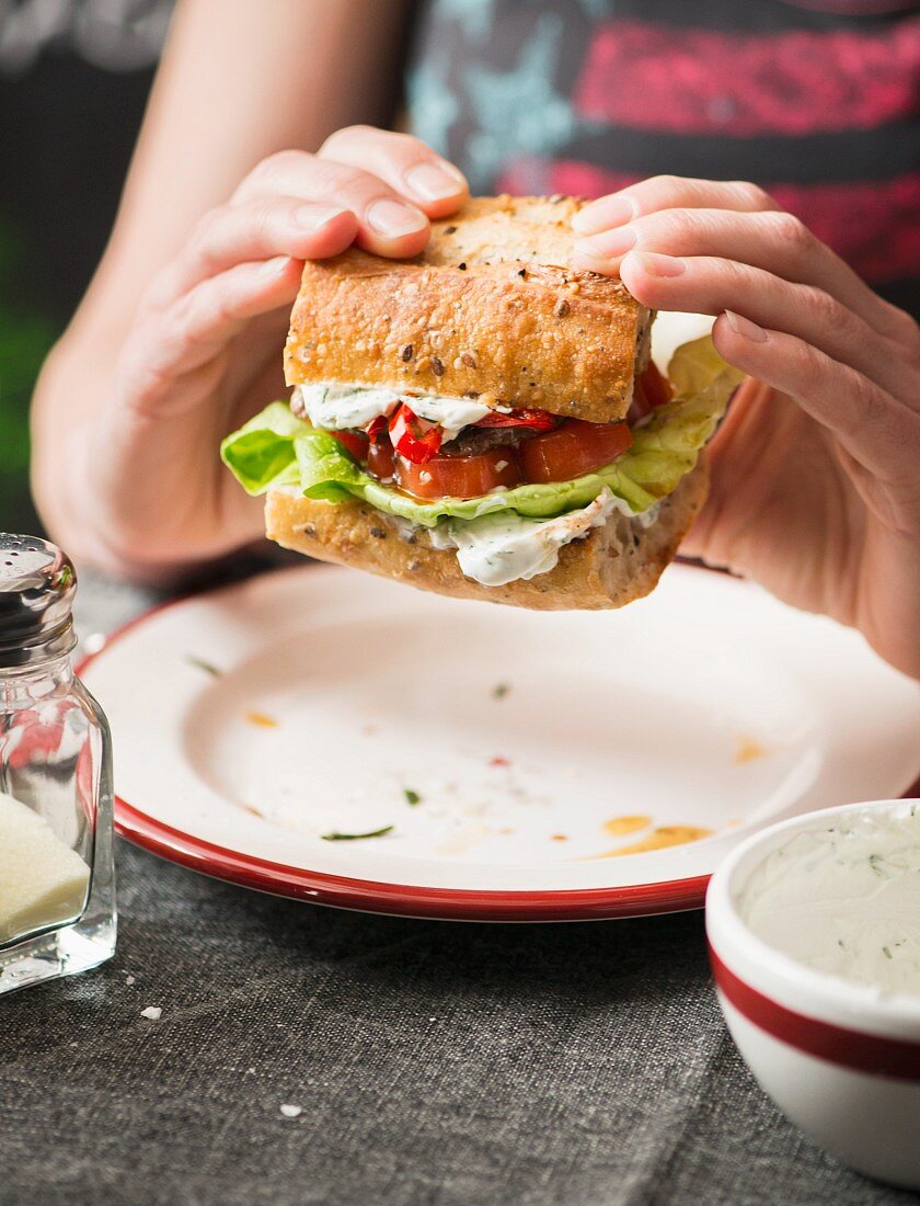 A woman eating barbecue burger with pesto in a diner