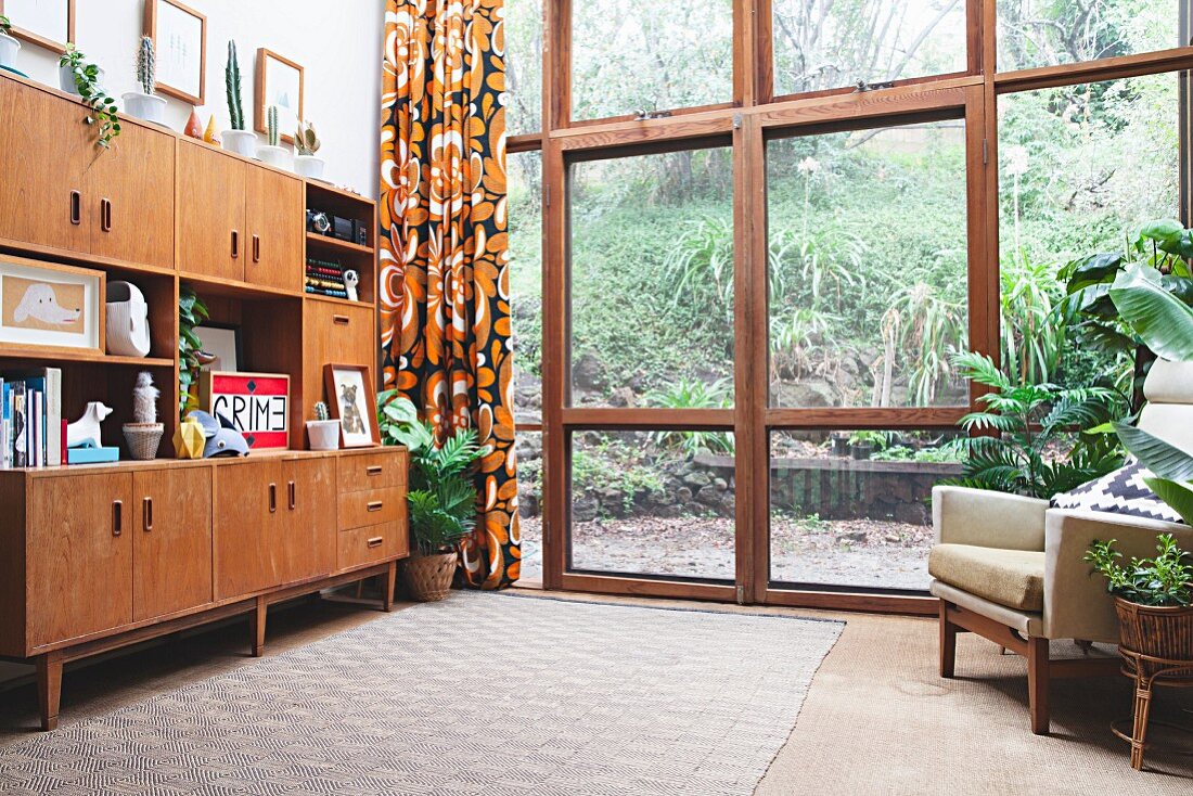 Retro living room cupboards next to glass wall with view of garden