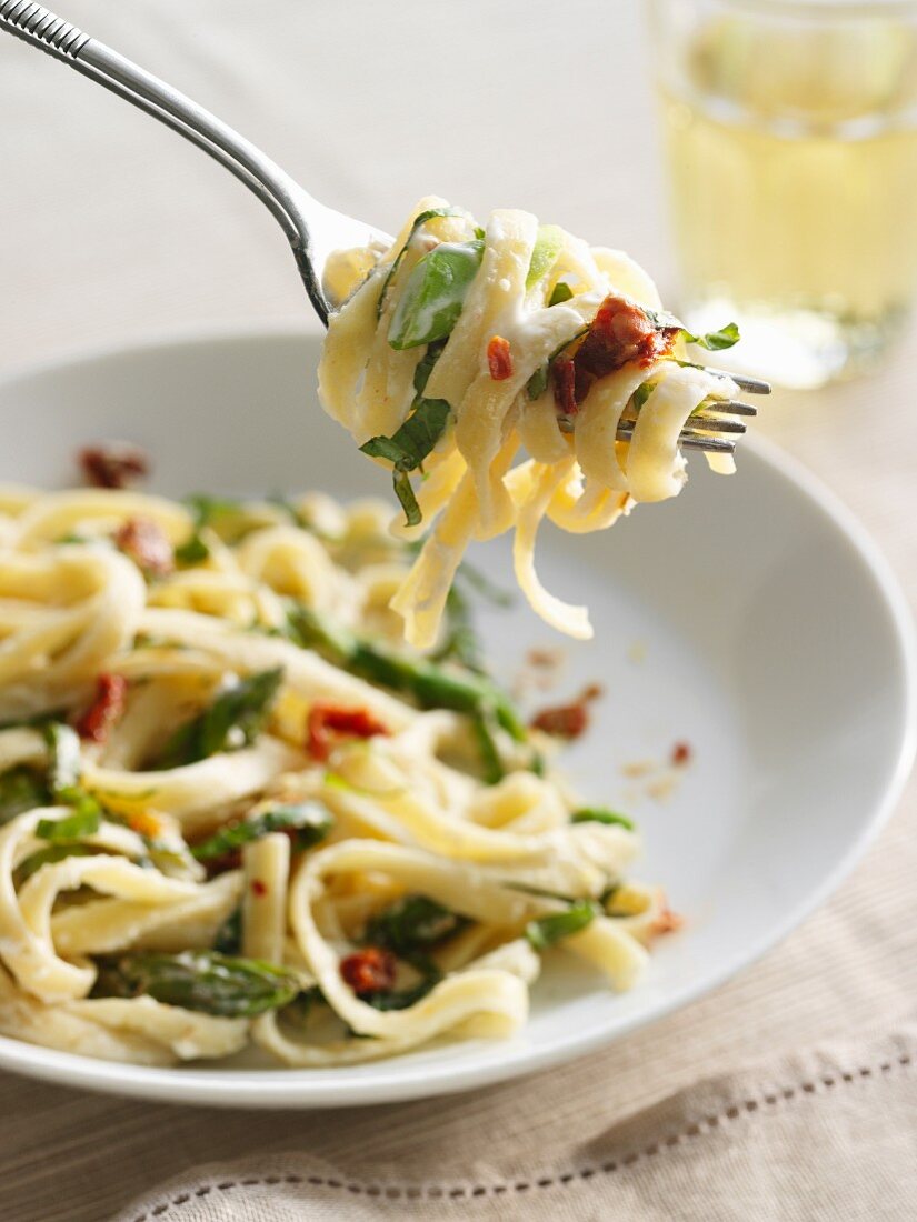 Fettuccine in cremiger Sauce mit grünem Spargel, getrockneten Tomaten und Basilikum