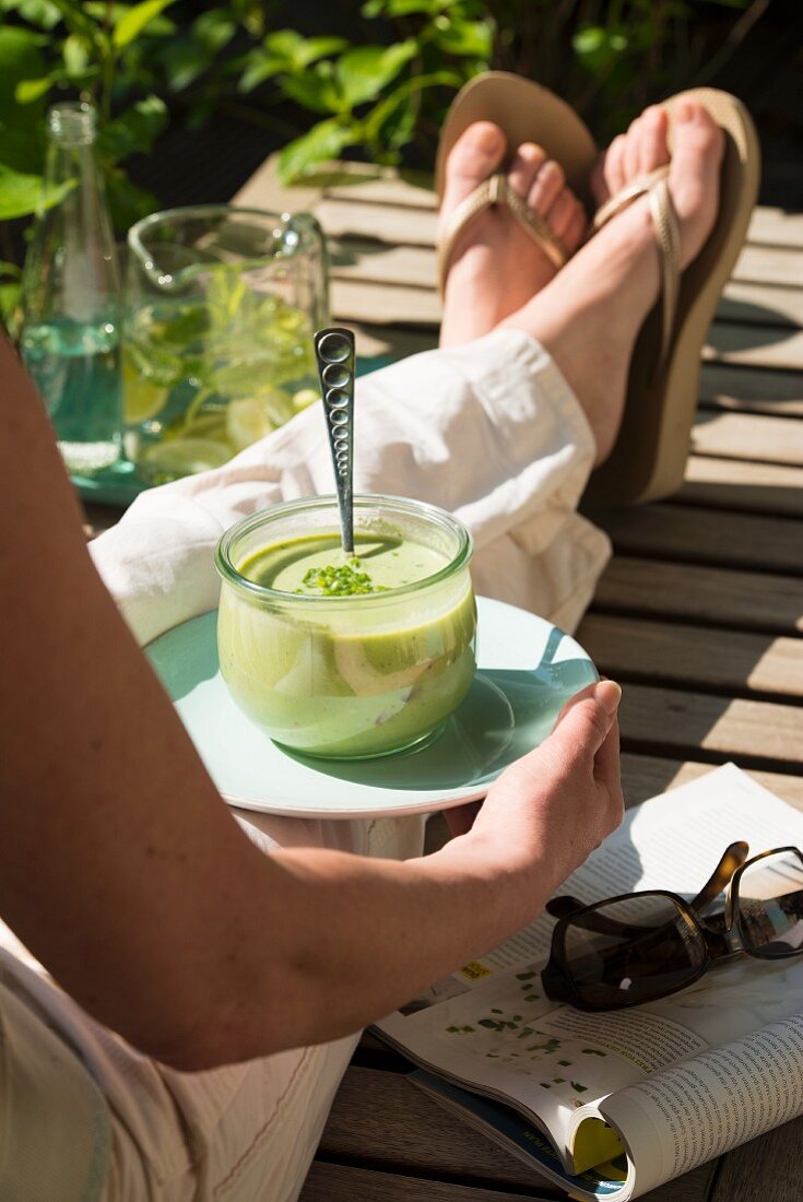 A woman with herb soup on a garden lounger