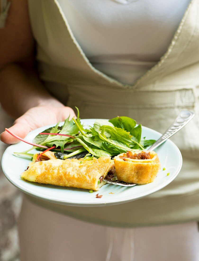 Frau serviert Omelett mit Salat im Garten