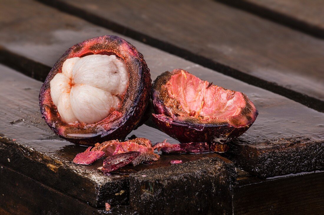 A sliced mangosteen on a wooden crate