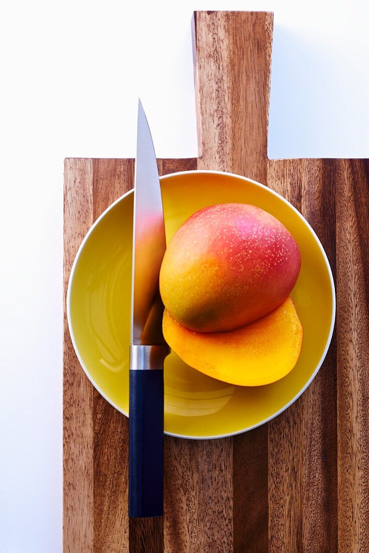 Halbierte Mango auf Teller mit Messer