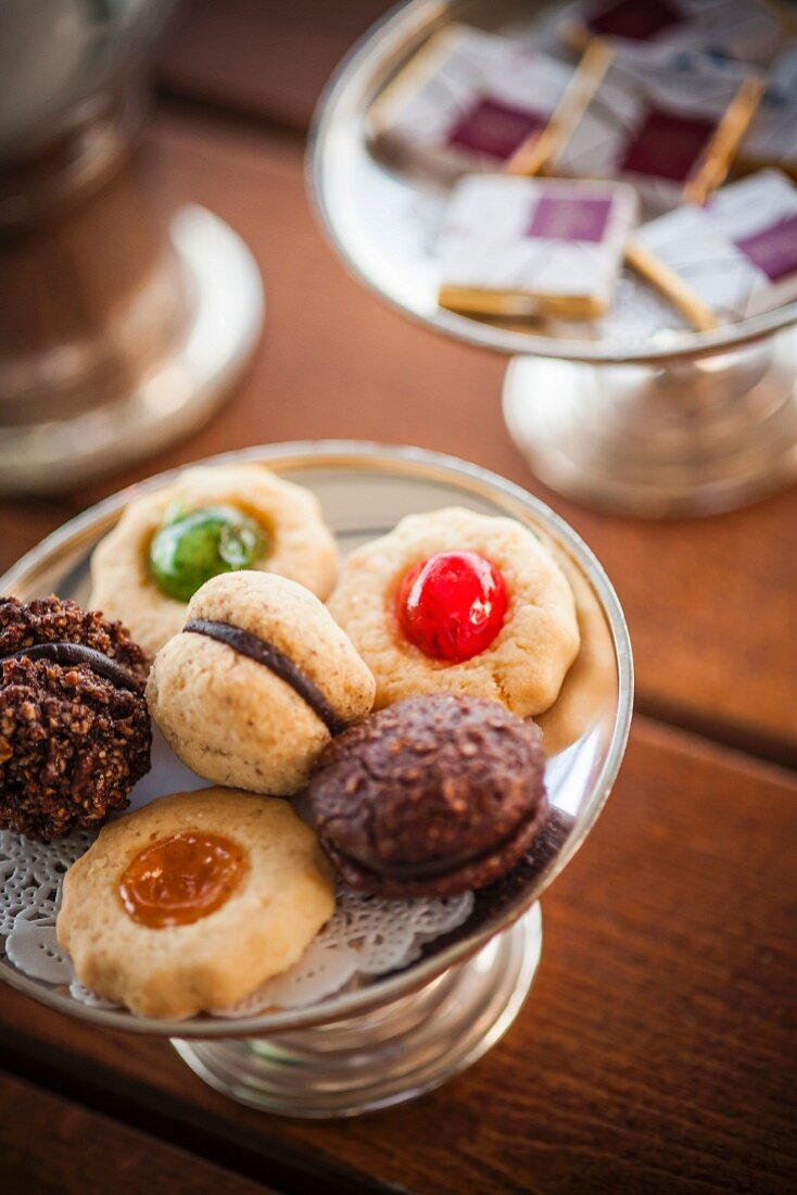 Various mini biscuits on a silver stand with a doily