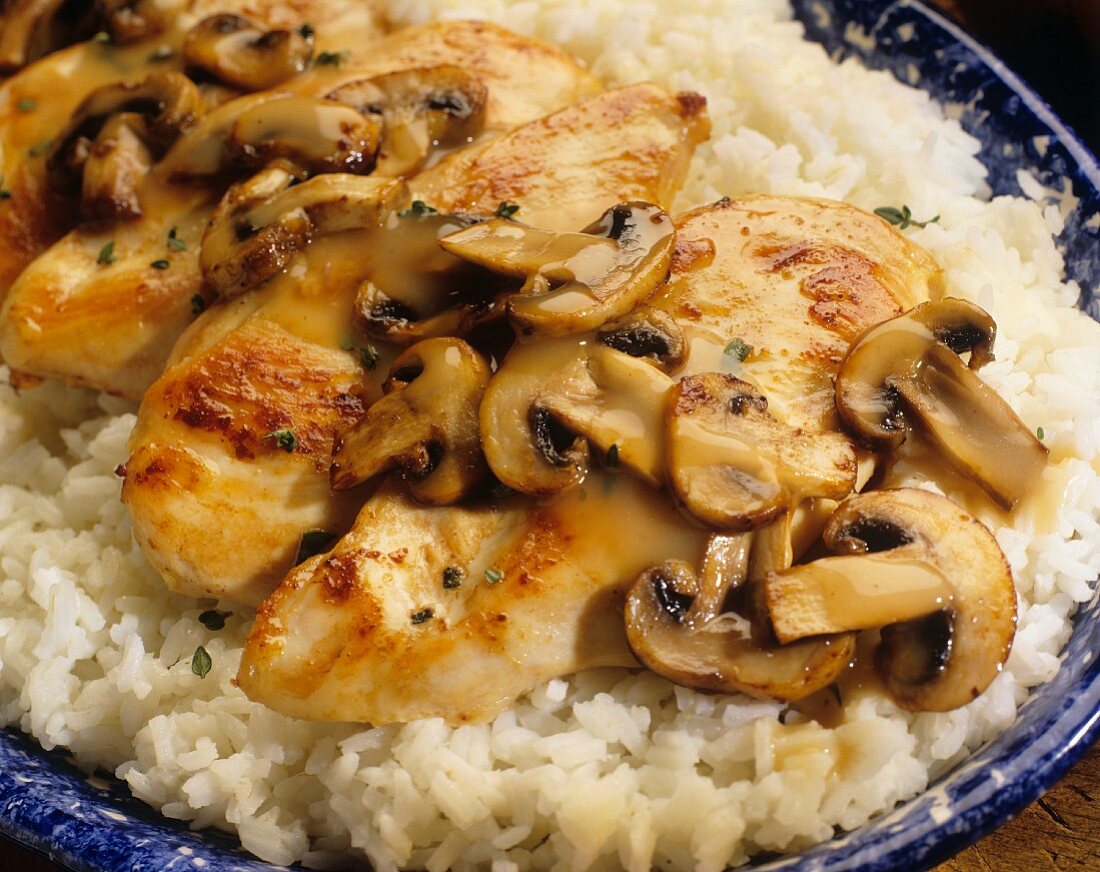 Sautéed chicken breast with mushrooms on a bed of rice (close-up)