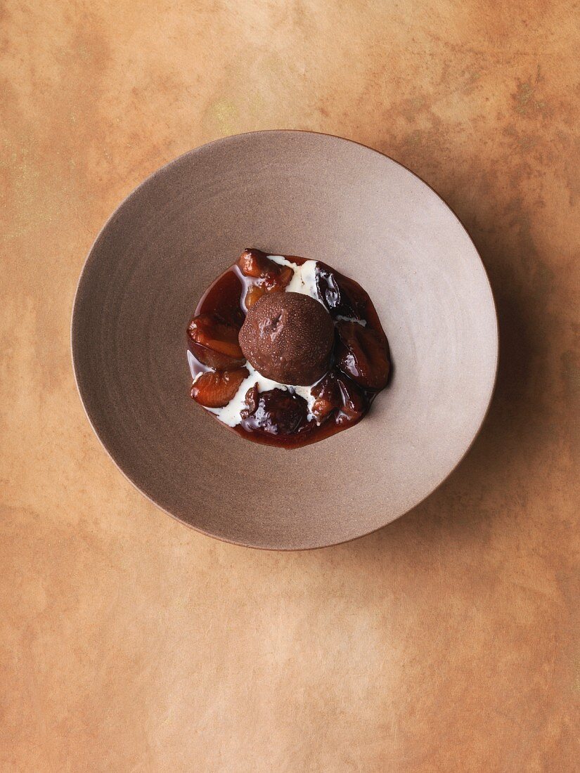 Chocolate ice cream bomb with pecan nuts and oranges on damson compote