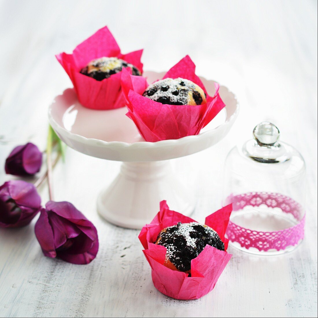 Blueberry muffins on a cake stand and next to a glass cloche