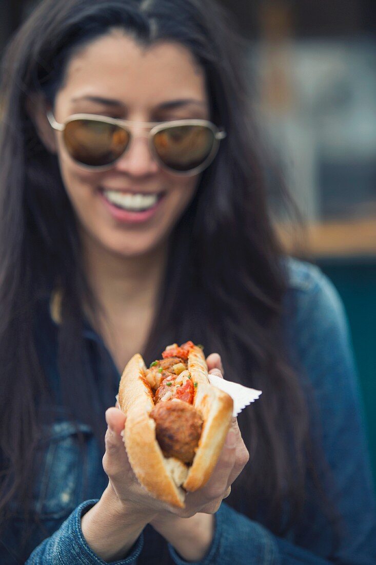 A woman holding a meatball sandwich