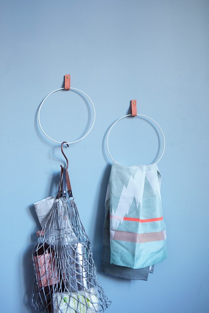 Hand-made towel rings hung on blue wall from leather straps