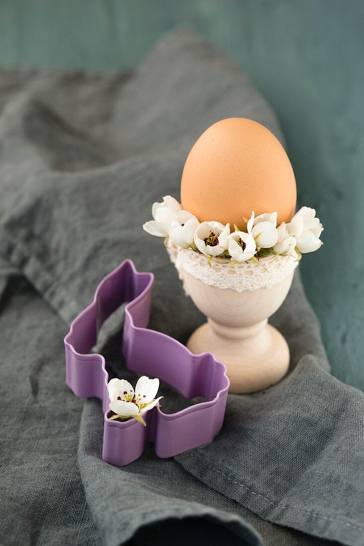 Egg cup decorated with pear blossom next to bunny-shaped pastry cutter