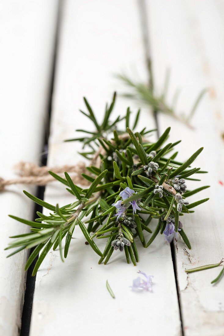 Flowering rosemary sprigs on a wooden surface