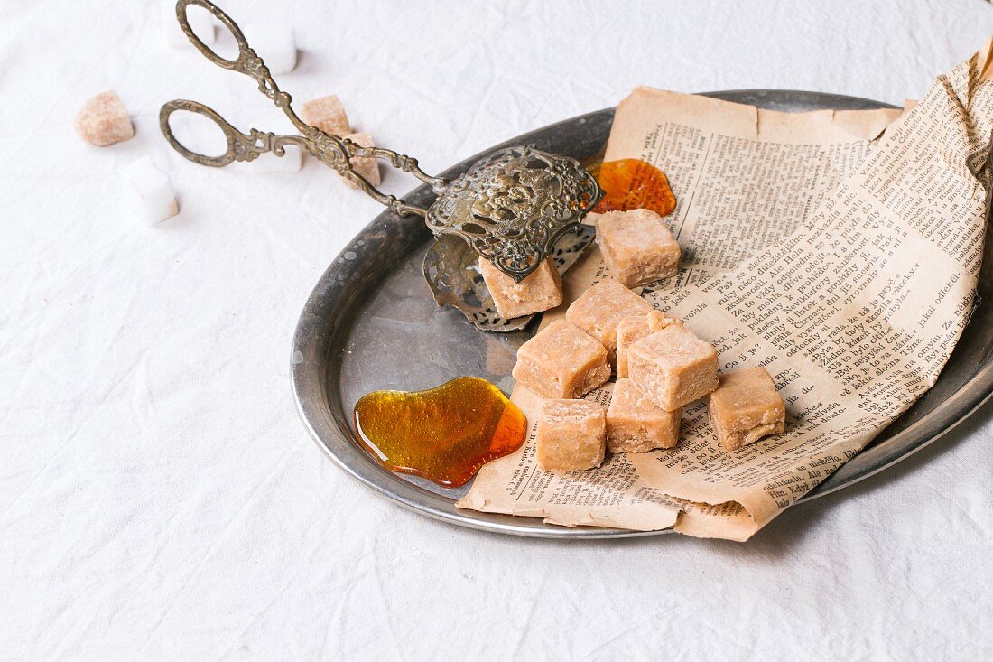 Caramel sweets and liquid caramel on an old newspaper on a tray