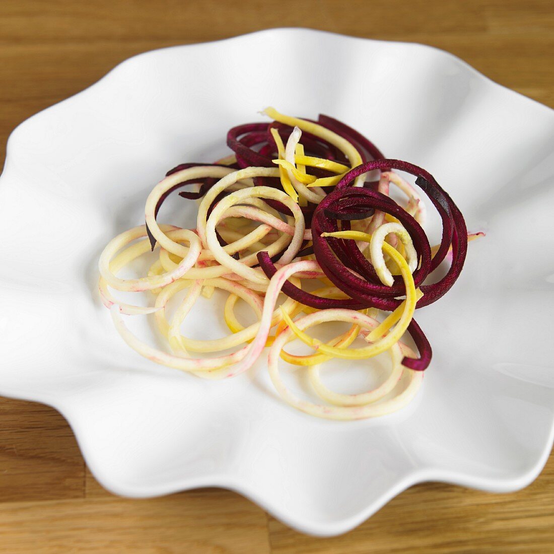 Vegetable spaghetti made from beetroot and yellow courgettes on a white plate