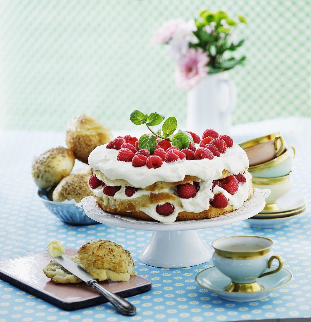 Raspberry cream cake, rolls and teacups