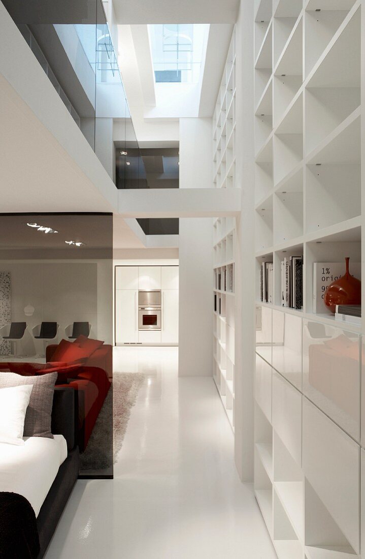 Open-plan, contemporary, showroom house with bedroom area and white shelving with many compartments