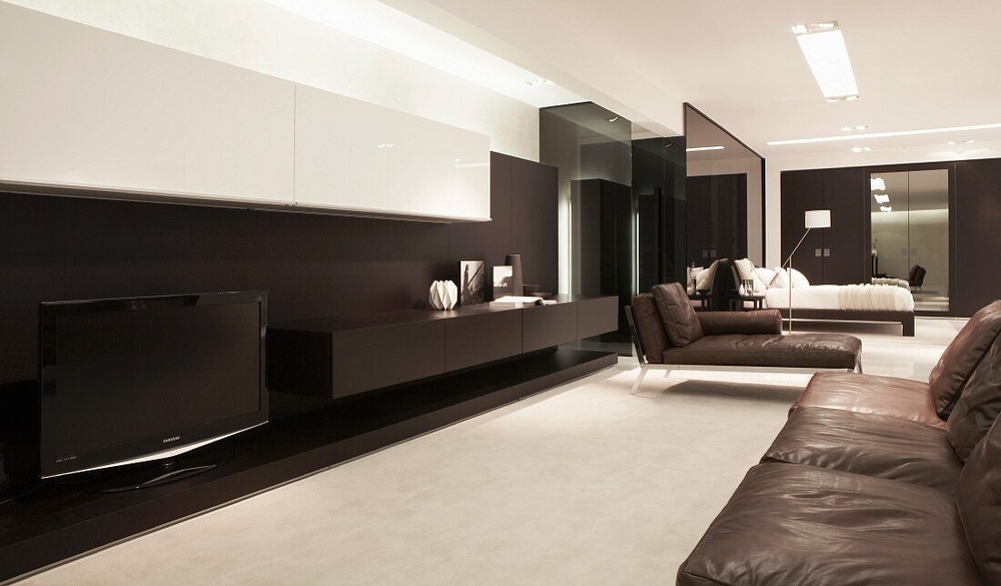 Open-plan lounge with black floating sideboard, white wall-mounted cabinet and modern chaise with black leather upholstery