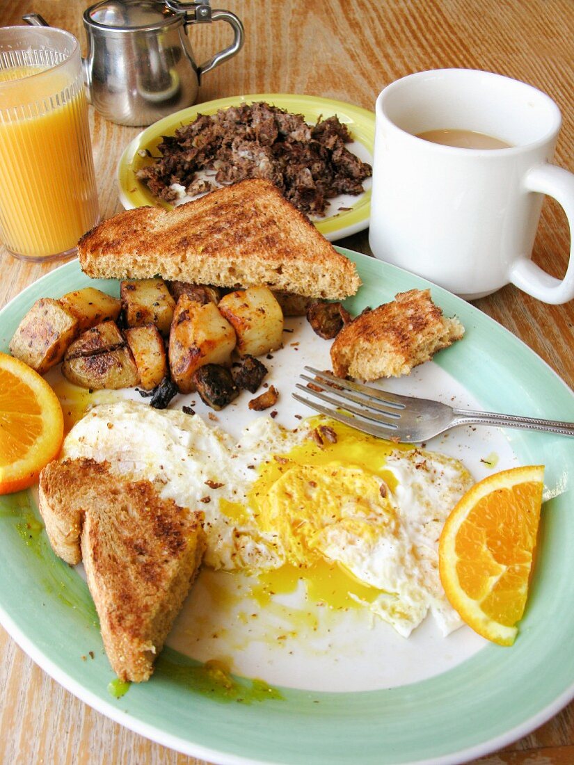 Englisches Frühstück mit Toast, Spiegelei, Bratkartoffeln, Kaffee & Saft