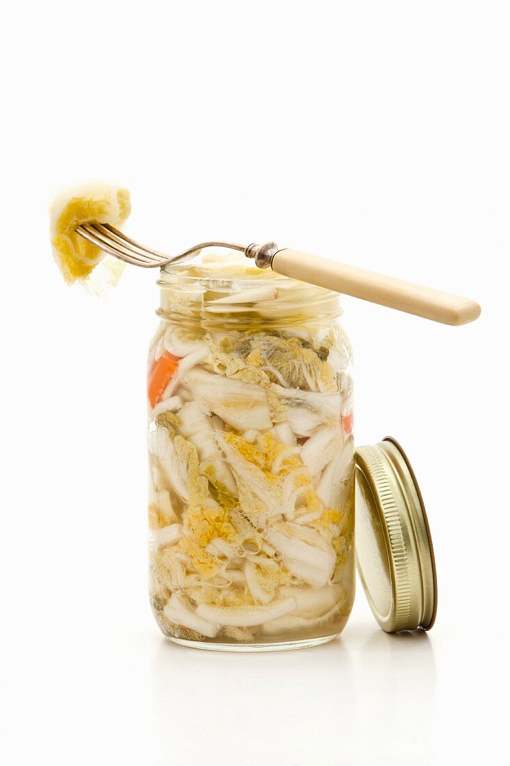 A jar of pickled bok choy on a white surface